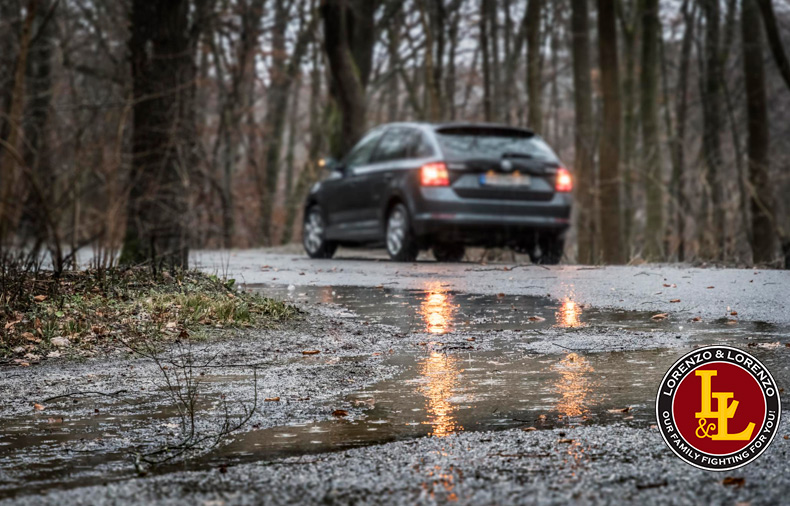 Puddle on road during storm with car in background